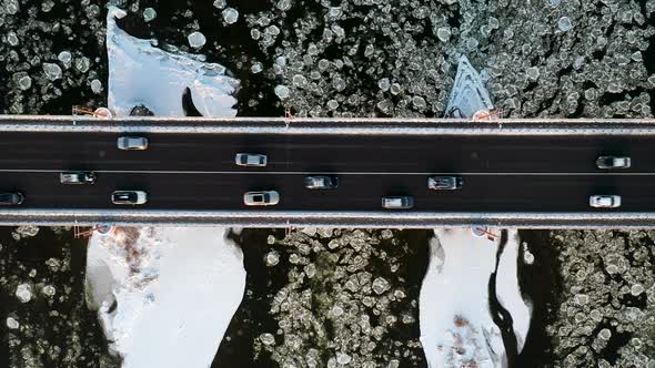 Aerial Top Down View Of Cars Driving On Bridge Over The River In Winter