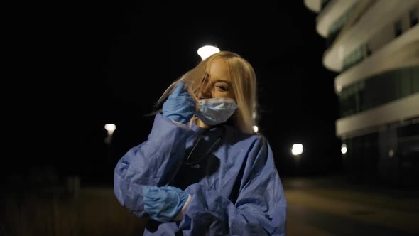 Cheerful Young Female Surgeon Takes Off Medical Mask During Night Shift alt