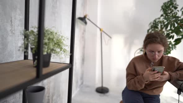 Close Up Portrait of a Teenage Girl Wearing Glasses with Her Smartphone alt