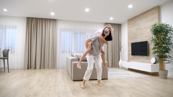 Happy Family Loving Young Mother Playing Piggyback with Preteen Daughter at Home in Living Room Slow