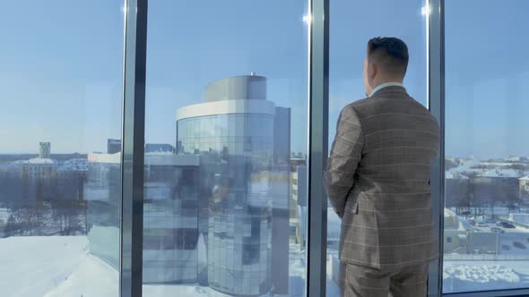 Portrait of Businessman in Suit Standing in Front of Window of Office Building Enjoying View of alt