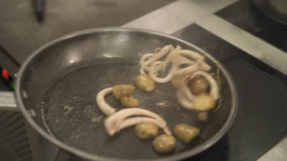 Close Up of Chef Frying Small Potatoes with Octopus in Restaurant
