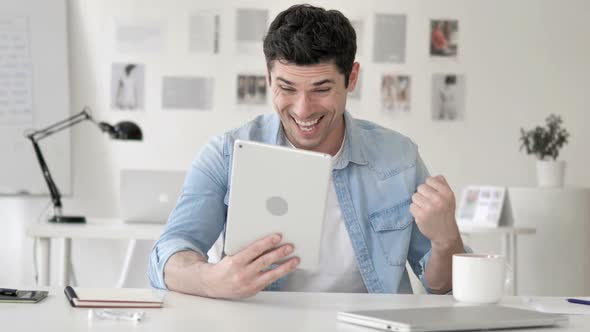 Casual Young Man Excited for Results on Tablet alt