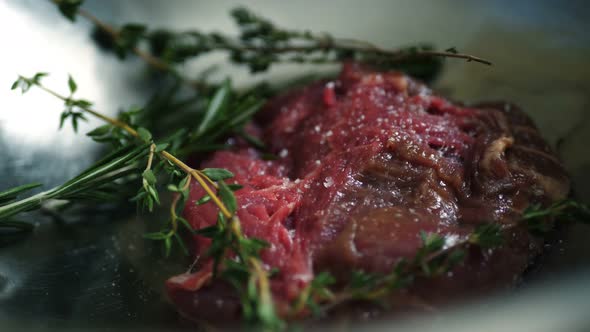 Hands of Male Chef Pouring Olive Oil Over Raw Meat Steak Closeup Shot