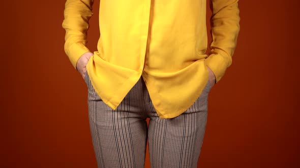 Front View on Body Part of Young Female in Yellow Blouse and Trousers on Orange Background alt