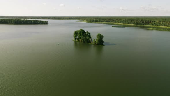 Top view of the lake, small island and the fisherman on the boat, 4k drone. alt