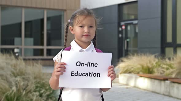 Cute Little Schoolgirl with Pigtails Stands with a Poster ONLINE EDUCATION