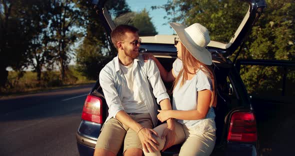 Couple Sitting in Car Trunk on Sunset