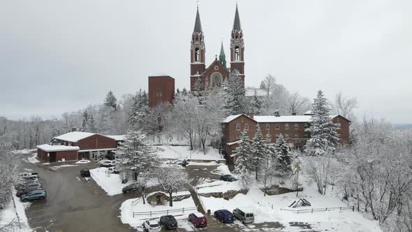 Winter drone view of church on mountain in snow. Snow covered mountain and trees.