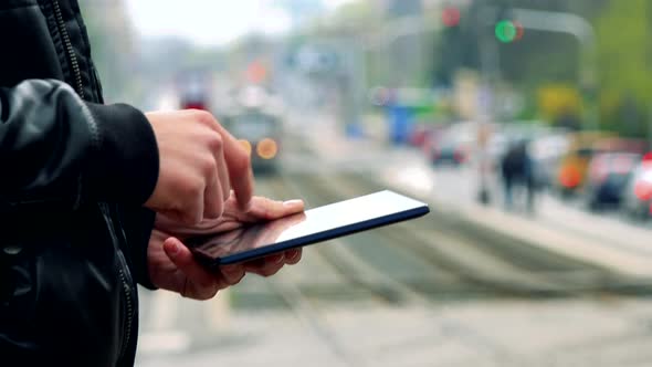 Young Man Stands and Works on Tablet Computer in Town - Detail of Hands with Tablet Computer alt
