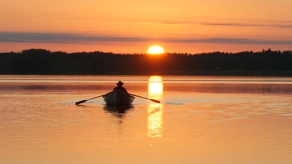 Sunset Over Lake and Man Rowing on Boat