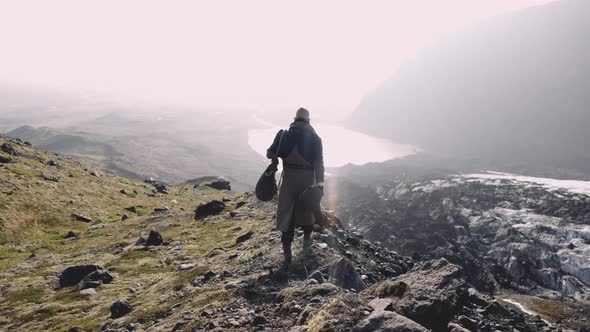 Man Walking Along Ridge To Looking Into Sunlit Valley alt