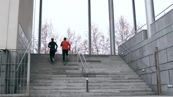 Two athletes training on steps running upstairs