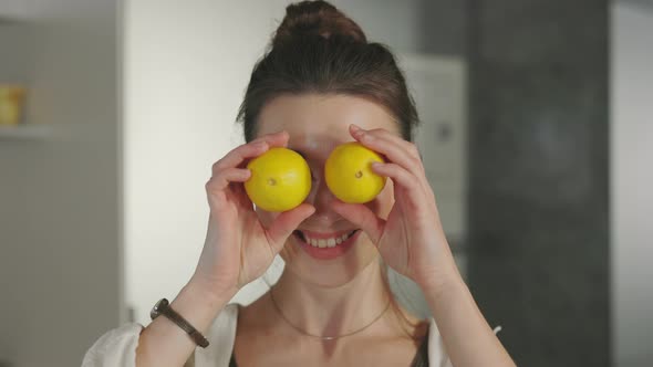 Playful Woman Covering Her Eyes with Lemons on Kitchen alt