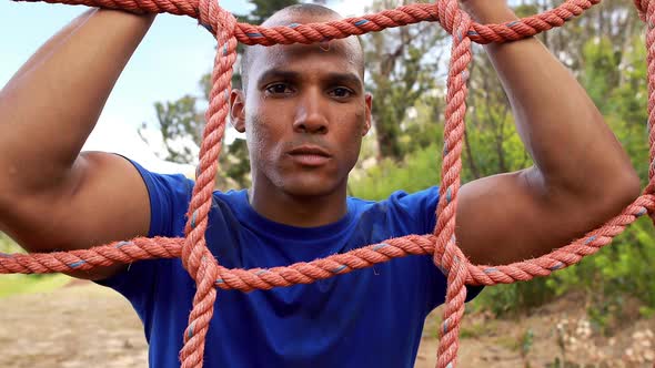 Fit man climbing a net during obstacle course alt