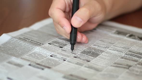 Man Highlighting The Advertisements In Newspaper With Marker