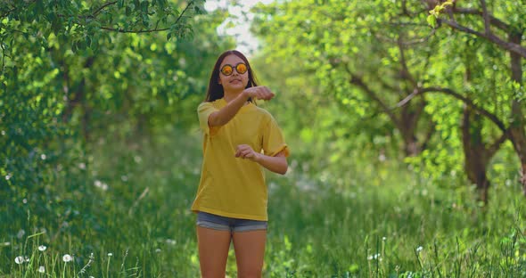 Teen Girl Fun Dancing in Glasses on the Street on the Grass alt
