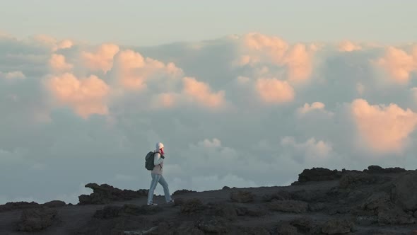 Breathtaking Epic Shot of Woman Hiking Mountain Above Pink Clouds Golden Sunset alt