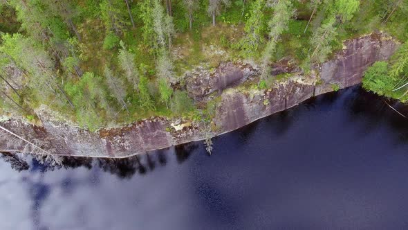 Drone shot of a water polished steep cliff in the boreal wilderness. Slowly descending and tilting u alt