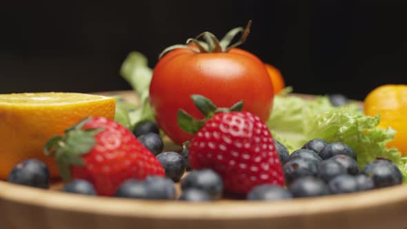 Variety of Color Fruits and Berries and Vegetables with Greens are Rotating on the Plate