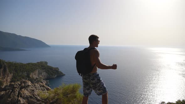 Male Hiker Standing on Peak and Victoriously Raising Arm Rejoicing Success alt