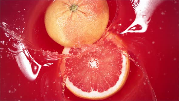 Grapefruit Falling on Juice with Splash and Divided in Half alt