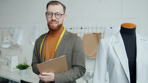 Handsome Young Man Dressmaker Standing in Workshop Against Workplace Background alt