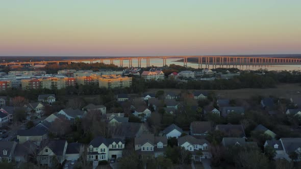 Aerial pull away view of neighborhood surrounding Wando River Bridge at sunset alt