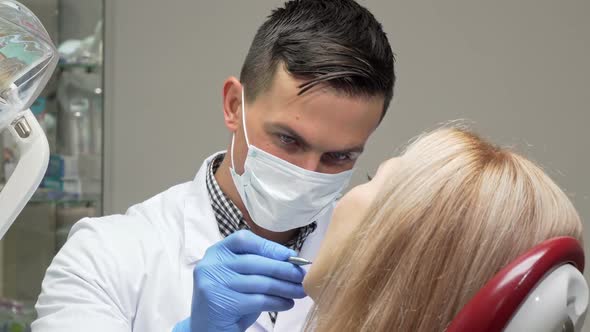 Cheerful Dentist in Medical Mask Laughing While Examining Teeth of a Patient alt