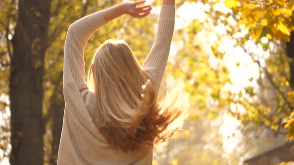 Fall outdoor. Fashionable lovable blonde woman dance laughing in autumn park. Beautiful Carefree gir