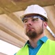 Closeup Portrait of a Young Master Builder in a Protective Helmet at a Construction Site - VideoHive Item for Sale