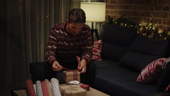 Young adult man packing Christmas gifts. Shot with RED helium camera in 8K alt