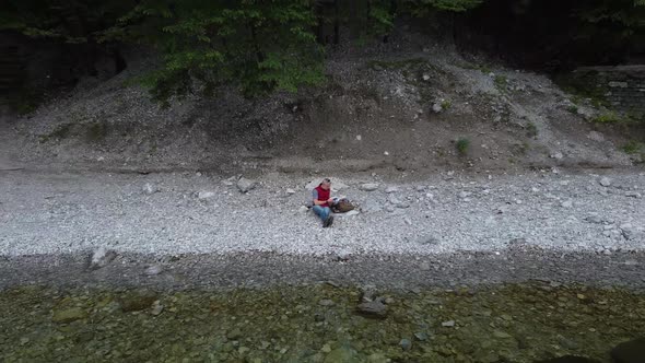 Lonely man relaxing on lakeshore and reading a book alt
