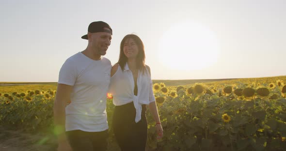 A Couple In Love Are Walking Through A Sunflower Field