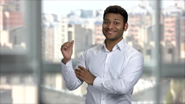Smiling Indian Man with Folded Arms Pointing Back alt
