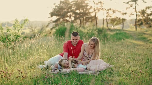 Young mom and dad with cute little daughter having fun outdoors in the woods. 
