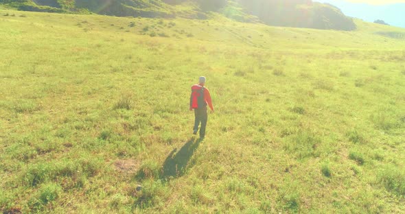 Flight Over Backpack Hiking Tourist Walking Across Green Mountain Field alt