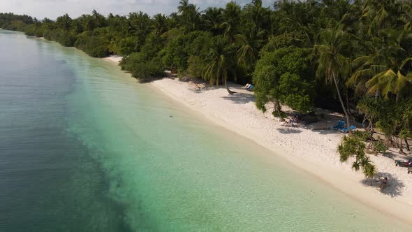 Drone flight over the sandy coast of the Maldives. On one side, great water. On the other hand, gree alt