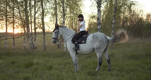 Young Girl on a Horse a Takes Off Protective Mask Against the Background of the Sunset alt