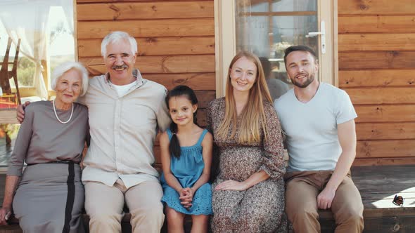 Portrait of Happy Big Family Embracing and Smiling on Wooden Porch alt