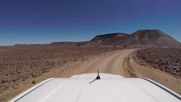 Car Driving on Gravel Road in Desert