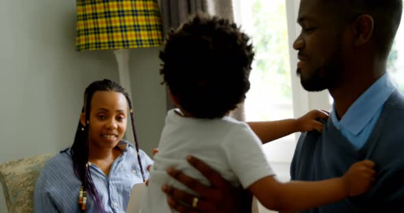 Side view of young black father playing with his son in living of comfortable home 4k alt