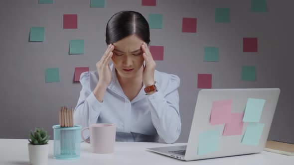 Asian woman working on a laptop has headache sitting