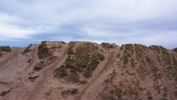 Aerial Along Sand Hills and Wide View on a Green Valley Against Moody Sky alt