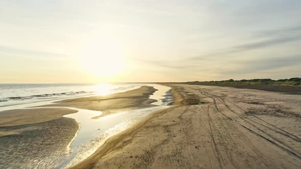 Drone Tracking Shot Along Beach in Denmark and Glare From Sun in the Background alt