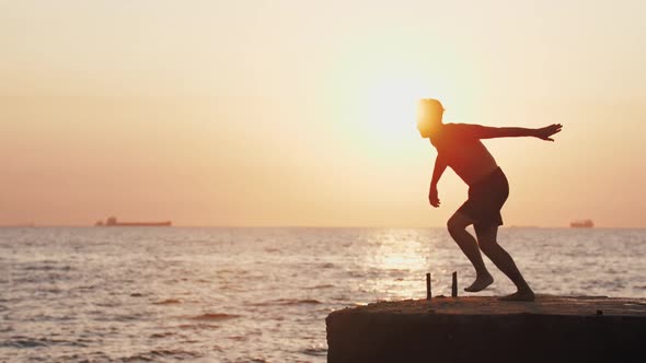 Young Man Jumping From Sea Pier and Doing Backflip During Beautiful Sunrise Super Slow Motion alt