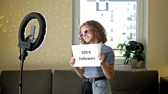 Cheerful Girl Blogger Shows a Poster with 200 Thousand Subscribers to the Camera alt