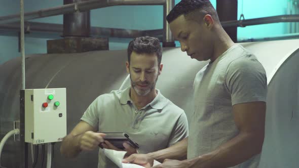 Industrial plant workers looking at blueprint alt