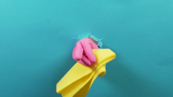 A Hand in a Rubber Pink Glove Holds a Yellow Cleaning Rag a Ragged Hole