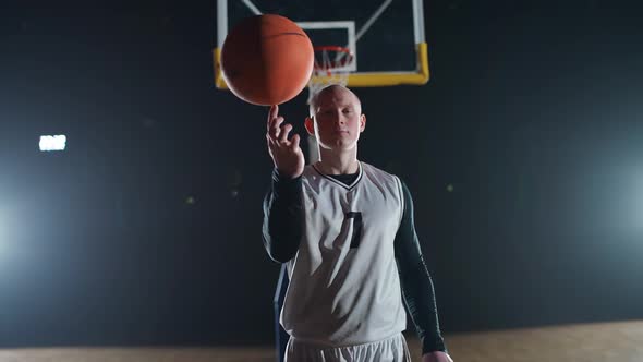 Sport Lifestyle Man Player Shows a Trick with a Spinning Basketball on His Finger and Looking at the alt